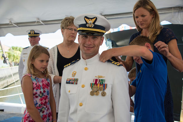 Lt. Cmdr. Brendan Harris receives new shoulder boards from his children during a promotion ceremony June 21, 2018, at the Federal Law Enforcement Training in Charleston, South Carolina. (U.S. Coast Guard/Ryan Dickinson)