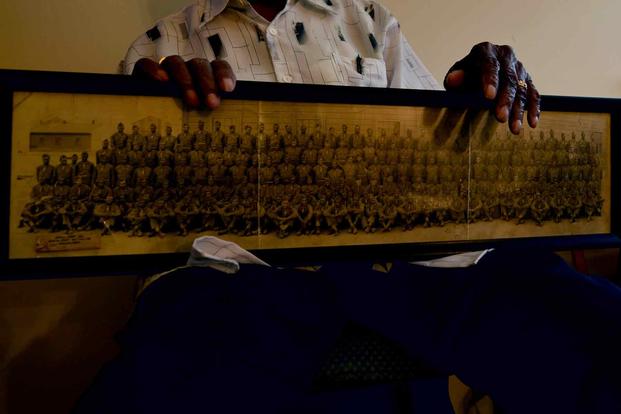 A retired veteran holds his military training class photo.