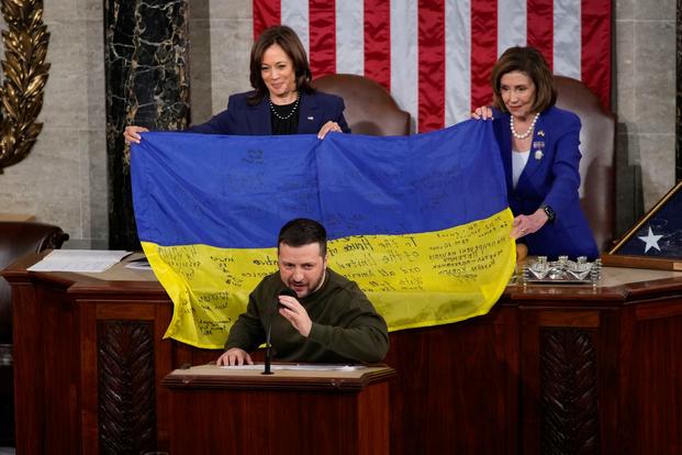 Vice President Kamala Harris and House Speaker Nancy Pelosi are presented with a Ukrainian flag.