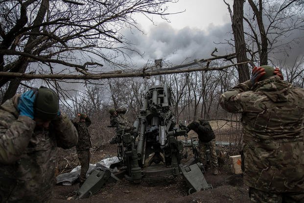Men from the Black Birds unit of the Ukrainian Territorial Defense Forces fire their M777 Howitzer