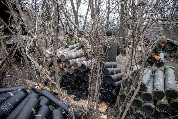 Ukrainian soldiers stack artillery shells.