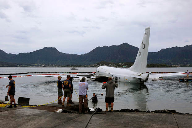Contractors place inflatable bags under a U.S. Navy P-8A in Kaneohe Bay, Hawaii.