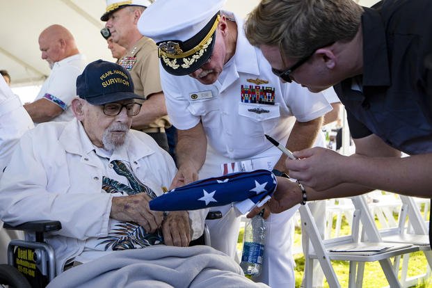 An attendee asks Pearl Harbor survivor Ira "Ike" Schab, 103, to sign an U.S. flag during the 82nd Pearl Harbor Remembrance Day ceremony