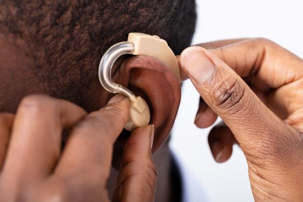 Doctor Inserting Hearing Aid In Patient's Ear