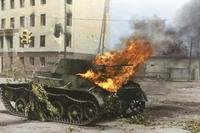 A Soviet T-55 tank burns by a roadside
