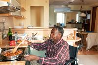man at home cooking in wheelchair