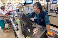 A commissary cashier checks groceries at Tinker Air Force Base, Oklahoma. Commissary cashiers are federal employees on the GS system. (U.S. Air Force/Margo Wright)