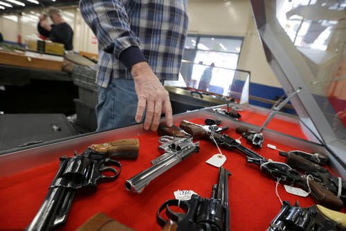 A dealer arranges handguns in a display case