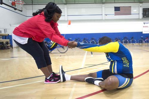 Caregiver helps husband stretch for the 2015 DoD Warrior Games